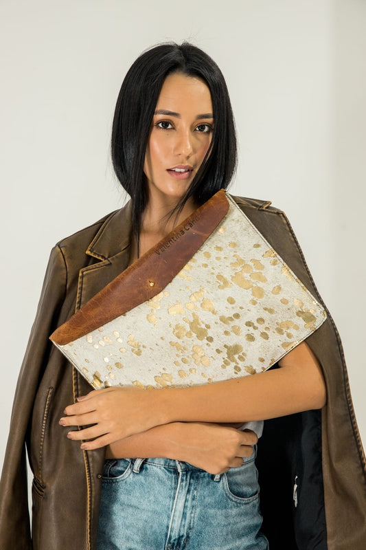 Mujer con un estuche para portátil en pelaje blanco con oro y solapa de cuero liso, con un nombre grabado en la solapa