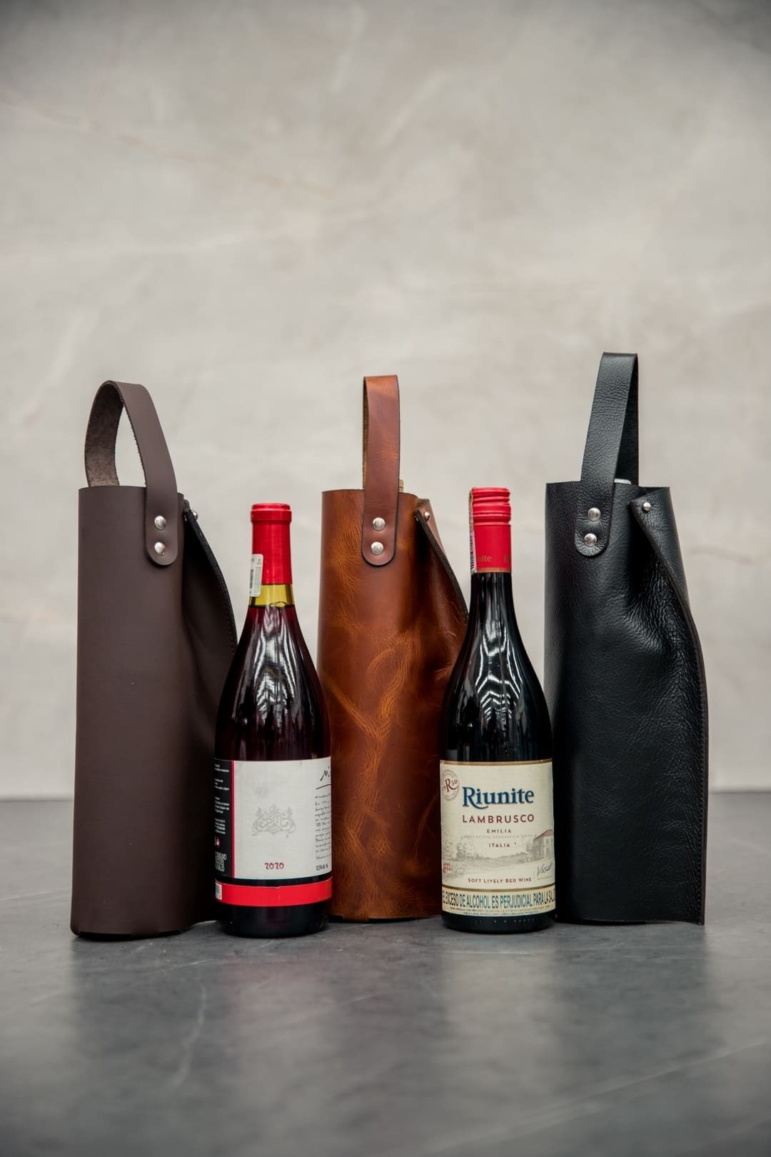 Forros de cuero con asa para botella de vino en café, rústico miel y negro, junto a dos botellas
