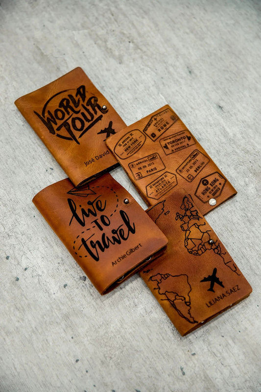 Cuatro portapasaportes sencillos de cuero rústico miel con los diseños World Tour, Sellos, Live to Travel y Mapa