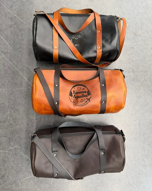 Tres maletas de cuero vistas desde arriba: negra con correas miel, rústico miel con un diseño grabado y café