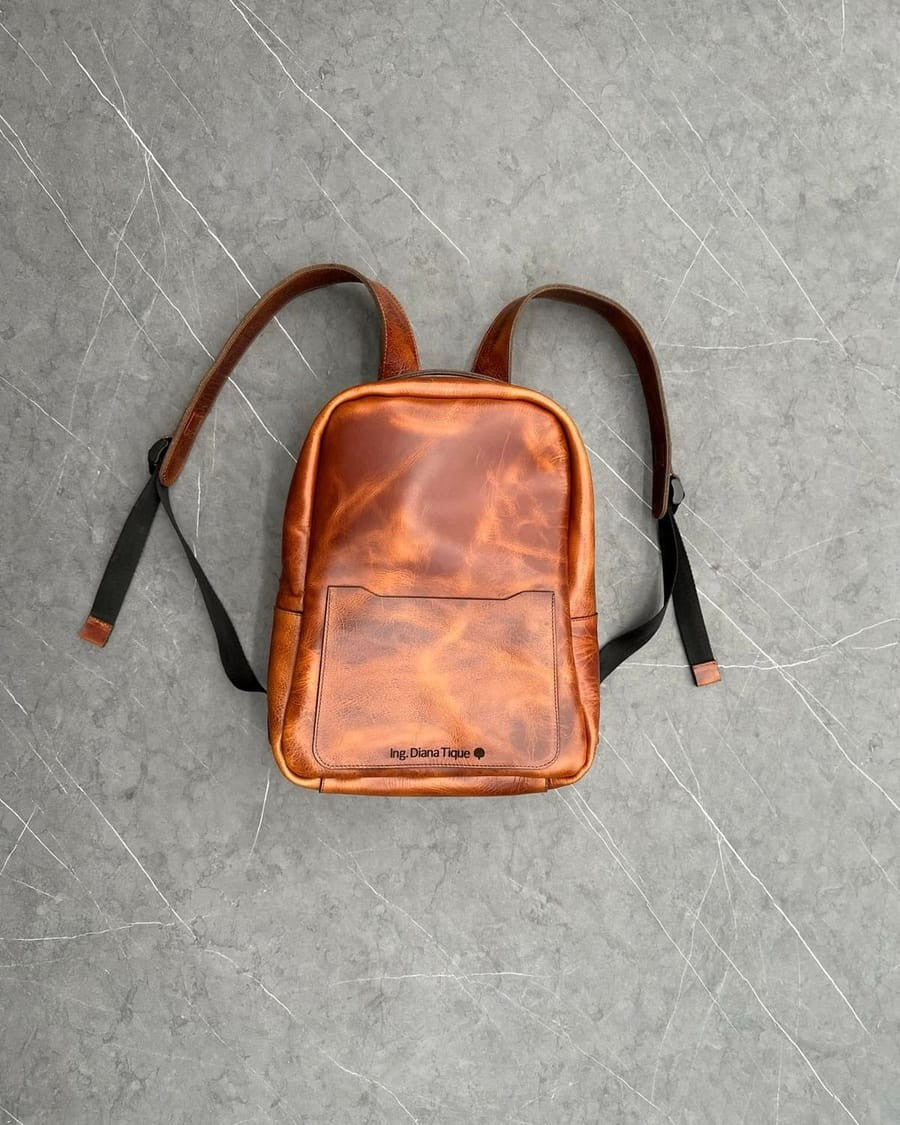 Maletín tipo morral de cuero rústico miel de frente, con un nombre grabado en el bolsillo